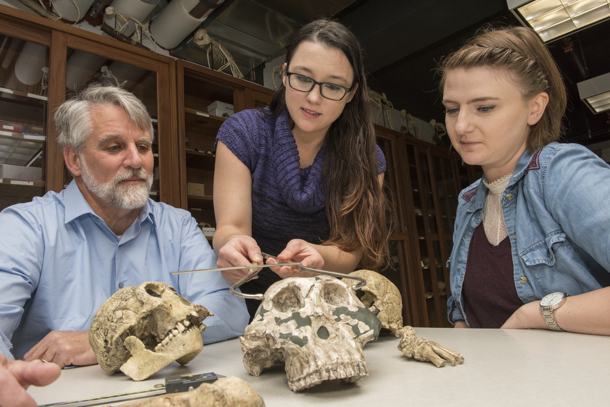 NIU faculty member talking with students with ancient homonid skulls