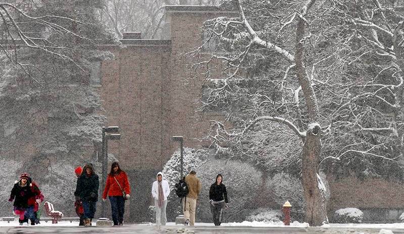 Winter scene with student walking across a snowy CUC campus