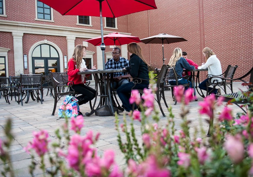 Spring Scene on Campus with pink flowers and students at a table at Lewis University